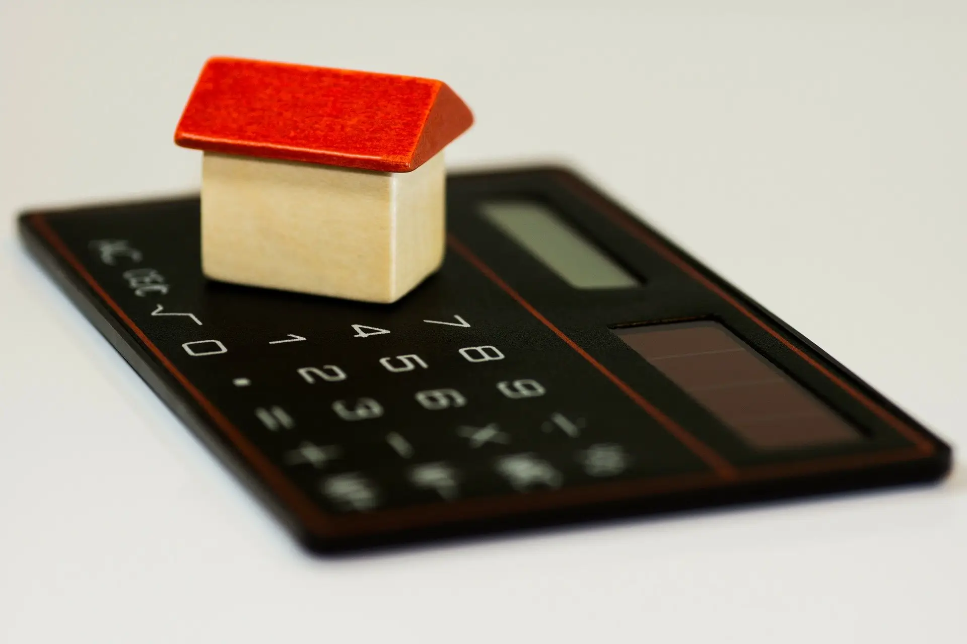 A small model house sitting on a calculator