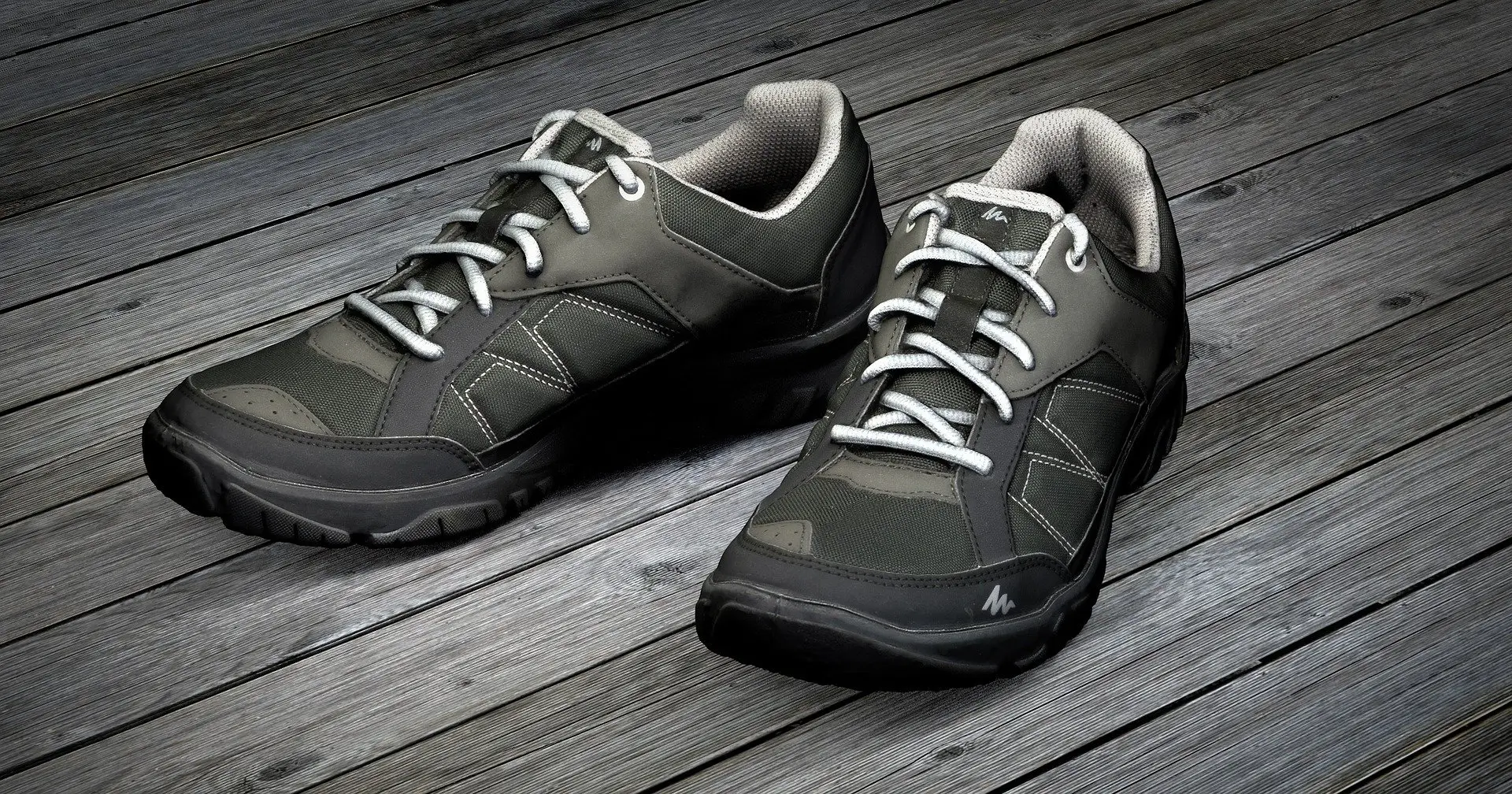 A pair of dark grey running shoes on a wooden floor